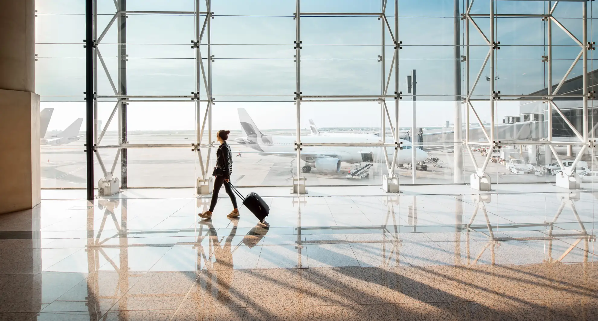 Traveler with luggage walking through a Boston airport terminal